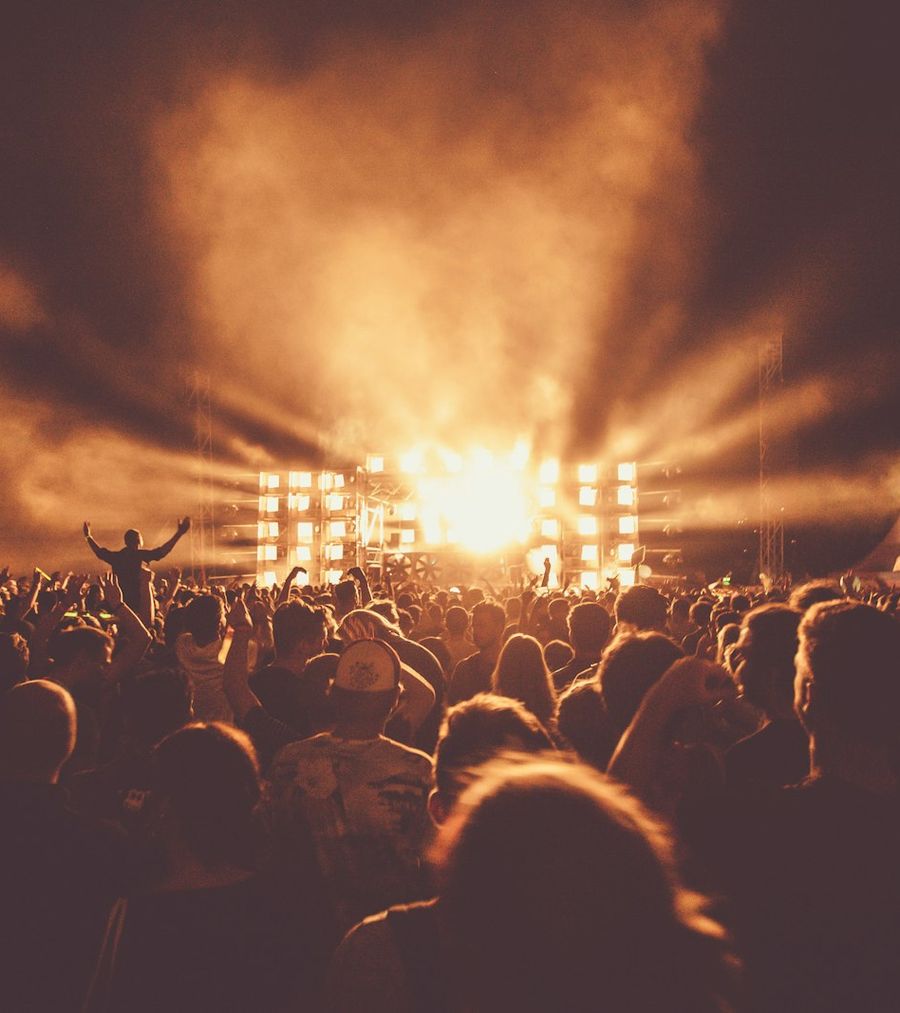 Warm amber stage lighting cutting through haze above a packed event crowd