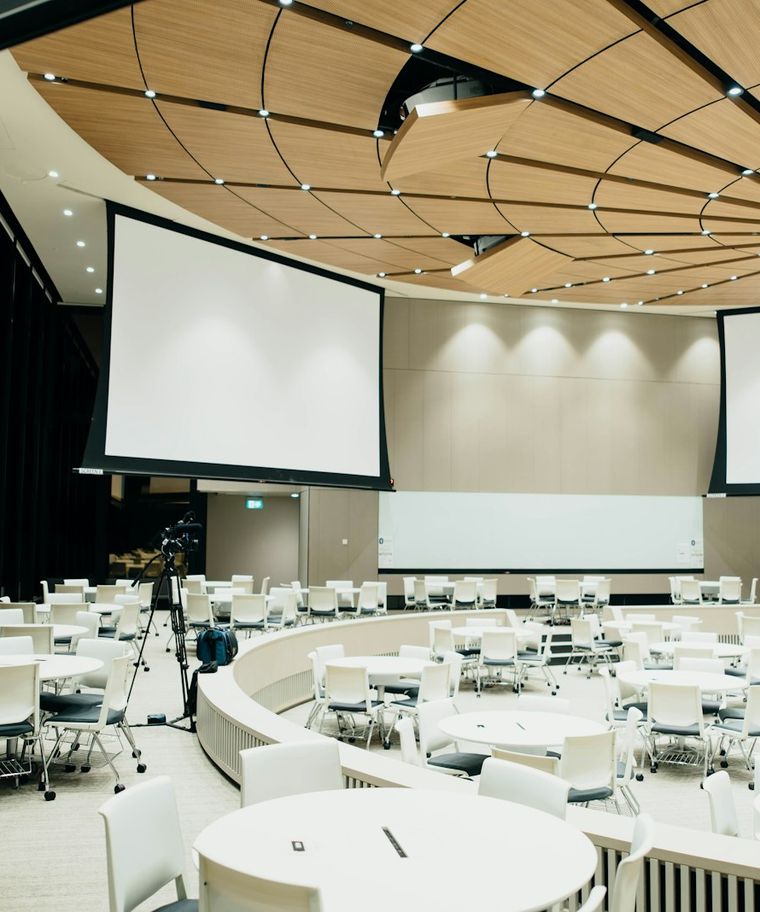 A conference room set with round tables and presentation screens